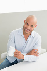 Smiling handsome man holding coffee cup at home