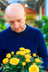 a man holding a bouquet of yellow roses,