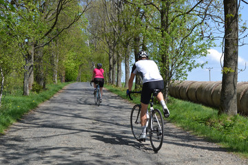 Spring bike riding through tree avenue, Young couple on bikes riding through tree avenue during beautiful spring day