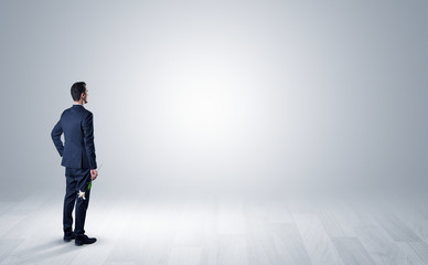 Man standing with his back in an empty room with object in his hand