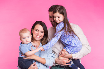 Portrait of Young Happy Mixed Race Family over pink background.