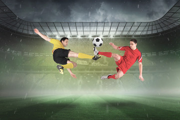 Obraz na płótnie Canvas Football players tackling for the ball against misty football stadium under spotlights