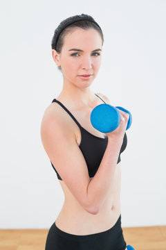 Serious fit woman exercising with dumbbell