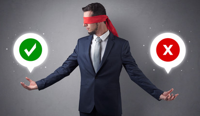Blindfolded businessman with checked and x mark above his hand