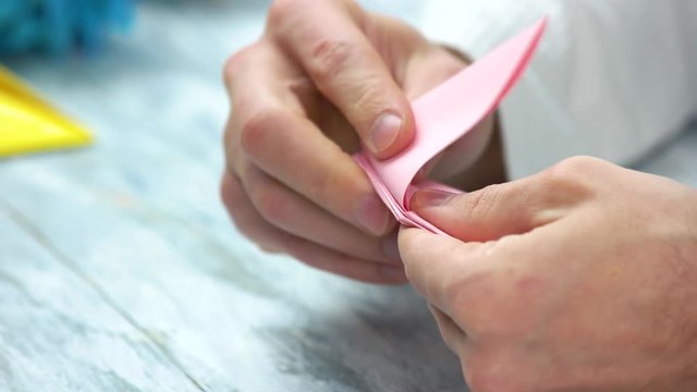 Man folding pink origami frog. How to make easy origami frog instructions. Japanese art of folding, crafts lesson.