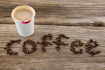 Coffee beans arranged in coffee word with disposable cups