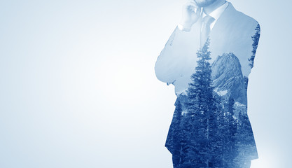 Young businessman standing and meditate with trees on the background 