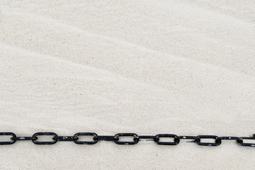 stretched black chain on windswept beach sand
