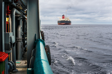 View from deck of AHTS ocean tug doing tanker lifting static towing. Tanker vessel on background....