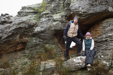 Smiling young couple on rock while on a hike