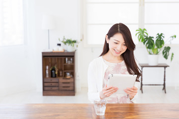 部屋でタブレットを見る女性