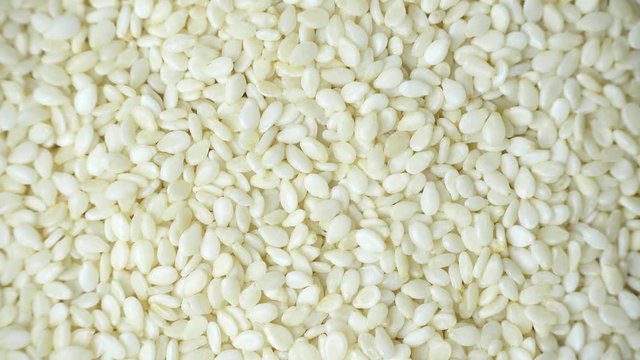 Rotation of white sesame seeds, close-up, top view, 4K