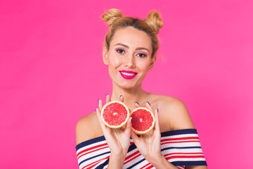 Portrait of happy girl holding halves of orange near face