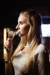Side view of thoughtful woman drinking martini