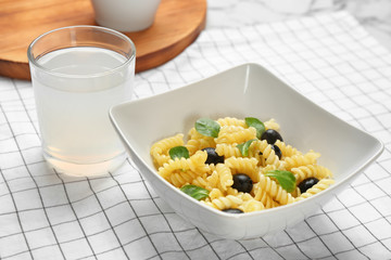 Bowl with delicious pasta salad on table