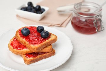 Toasts with jam and berries on plate, closeup