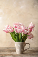 Cup with beautiful tulips for Mother's Day on table
