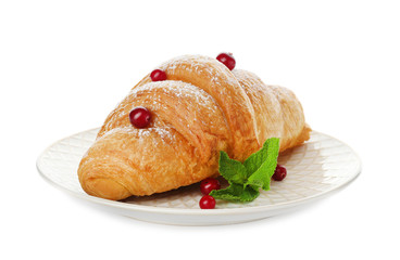 Tasty croissant with sugar powder and berries on plate against white background
