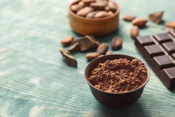 Composition with cocoa powder and chocolate bar on wooden background