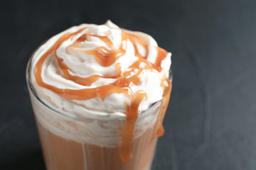 Glass with delicious caramel frappe on grey background, closeup