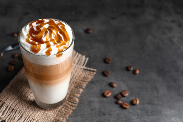 Glass with delicious caramel frappe on grey background