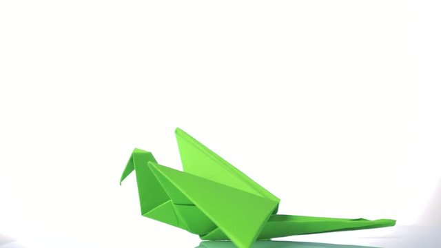 Green paper crane on white background. Traditional origami bird crane made from green paper. Japanese culture and paper craft.