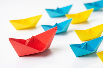 Leadership, influencer, KOL, key opinion leader concept, big red paper ship origami in front of others small yellow and blue fleet