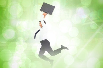 Smiling businessman leaping while briefcase against green abstract light spot design