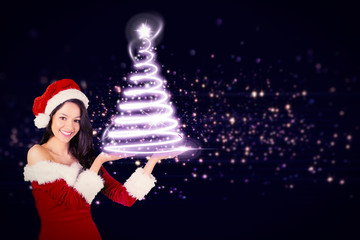 Pretty girl presenting in santa outfit  against glowing christmas tree