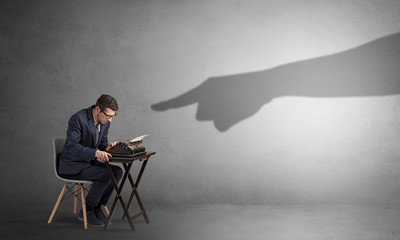 Shadow hand pointing at a small afraid worker
