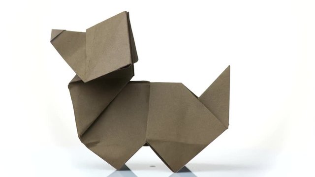 Paper dog figurine on white background. Origami dog made by child. Simple design of paper animal.