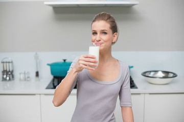 Obraz na płótnie Canvas Smiling gorgeous model looking at camera drinking glass of milk
