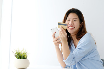 Young asian woman holding credit card and using smart phone for shopping online, business and technology concept, online payment, digital money