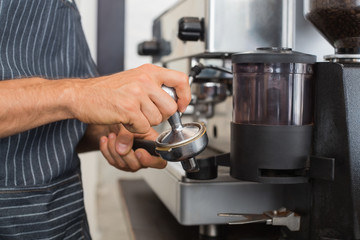 Mid section of a barista prepares espresso in coffees hop