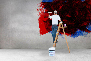 Man on ladder painting with roller against grey room