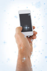 Male hand holding a smartphone against snow falling