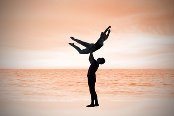 Ballet partners dancing gracefully together against beach scene