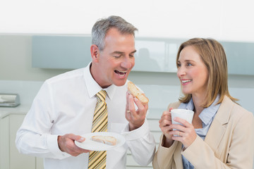 Obraz na płótnie Canvas Happy business couple having breakfast in kitchen