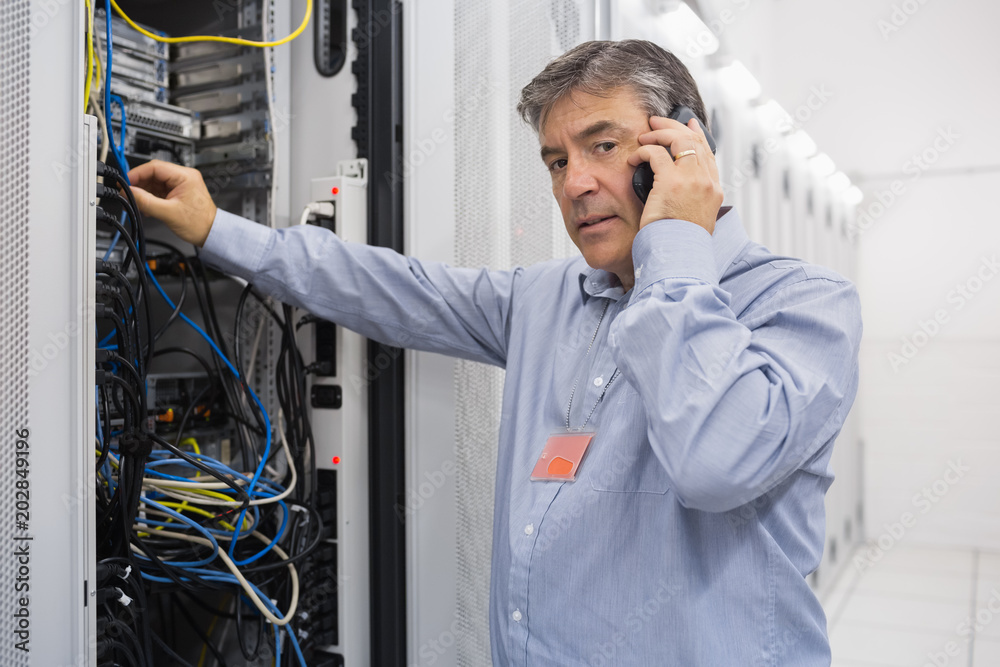 Poster technician working on server and phoning