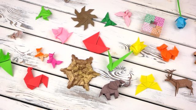 Set of origami objects on rustic wooden background. Collection of origami animals, flowers and abstract models on white wood. Childrens crafts contest.