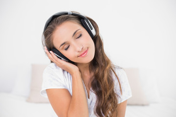 Naklejka premium Peaceful smiling brunette listening to music with closed eyes