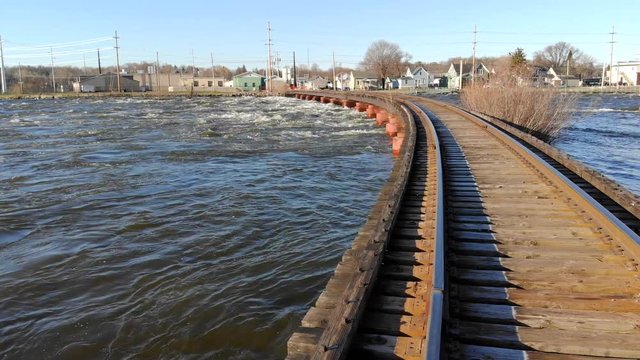 Spring thaw causes high water, rapids by railroad trestle bridge