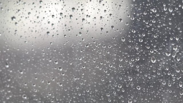 4k The rain drifted to the glass. Causing a drop of water. Spread the mirror on a rainy day, feeling lonely and lonely. Use as a background or background for a job.