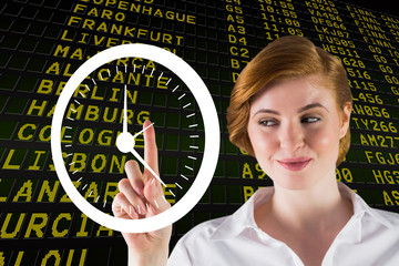 Businesswoman smiling and pointing to a white clock against black airport departures board