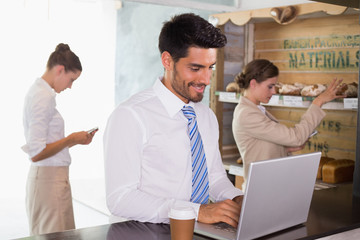 Businessman using laptop in office cafeteria