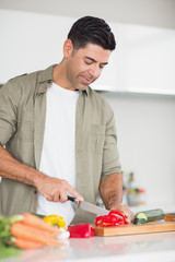 Fototapeta premium Smiling man chopping vegetables in the kitchen