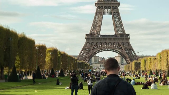 PARIS, FRANCE - SEPTEMBER 29, 2017: Timelapse shot of people walking and relaxing on green lawn of Champ de Mars near the Eiffel Tower