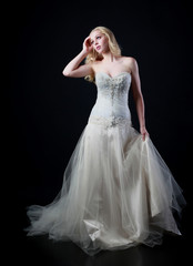 Fototapeta premium pełnej długości portret kobiety na sobie białą suknię ślubną. stojąca trucizna czarne studio tło.