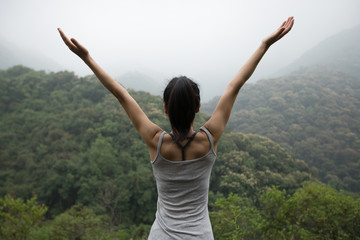 Happy woman with outstretched arms enjoying the view on morning mountain valley