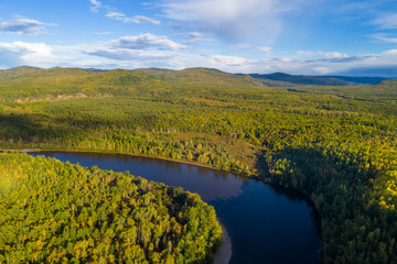 Aerial drone View of autumn mountains and small river with forests in sunrise soft light. Majestic landscape.